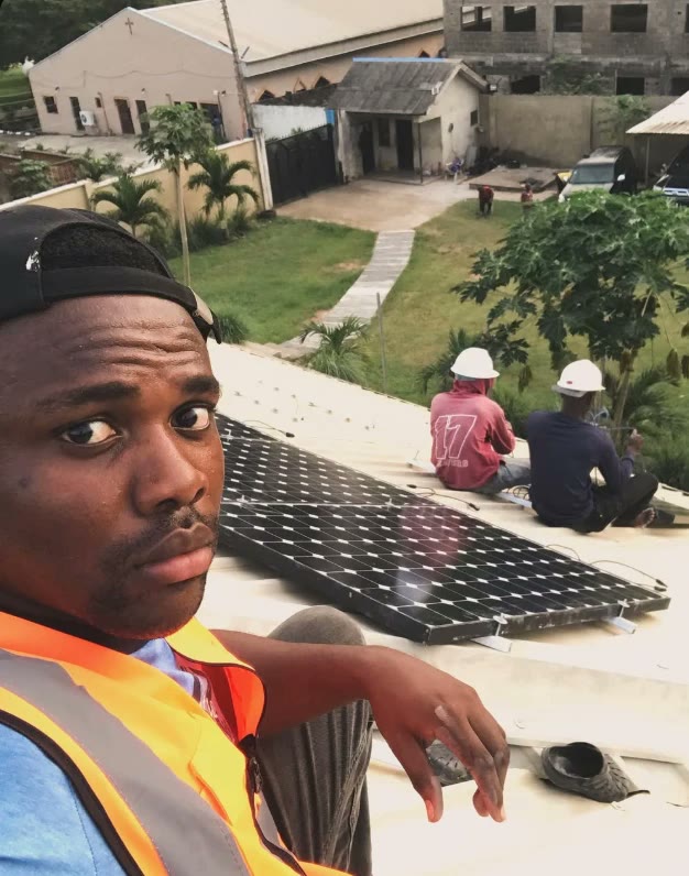 A Johnson D-Energies crew member on a rooftop while two installers fit solar panels
