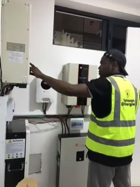 A technician inspecting a wall-mounted inverter system